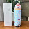 A light blue vacuum insulated water bottle with a pink lid and straw is shown next to its white packaging box.