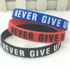 Trois bracelets en silicone bleu, rouge et noir avec le texte Never Give Up