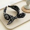 Black paisley bandana headband tied in a bow resting on a light tray.