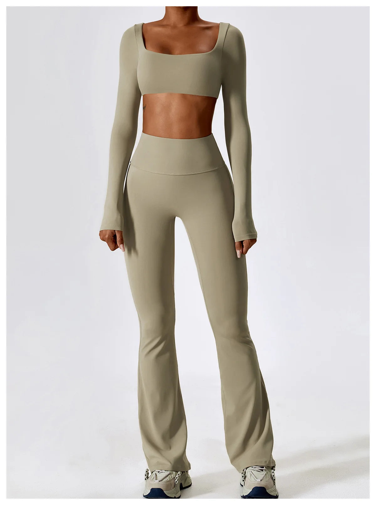 A woman models a beige women's performance tracksuit set consisting of a cropped top and matching full-length pants.