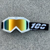 White protective goggles with orange-tinted lenses and a black strap resting on a gray surface.