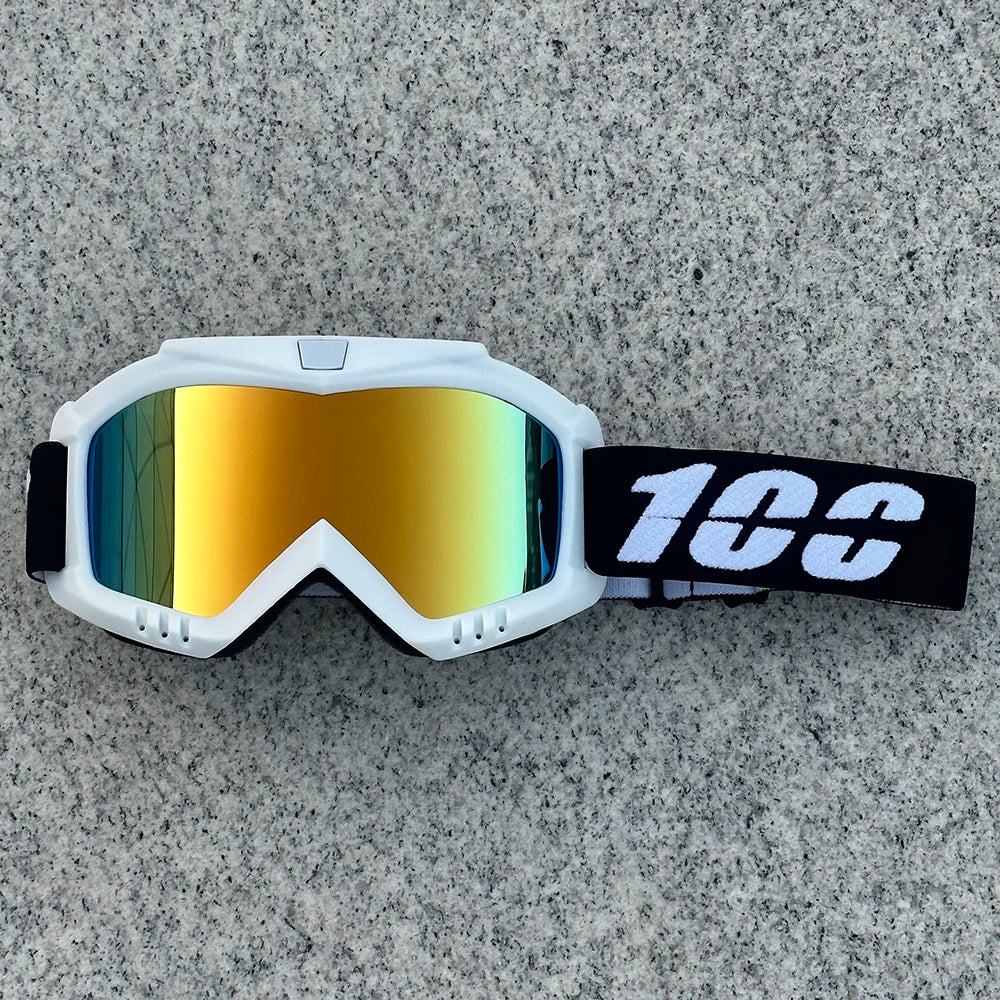 White protective goggles with orange-tinted lenses and a black strap resting on a gray surface.