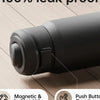 A close-up view of a black insulated sports water bottle with a magnetic and locking lid on a wooden surface.
