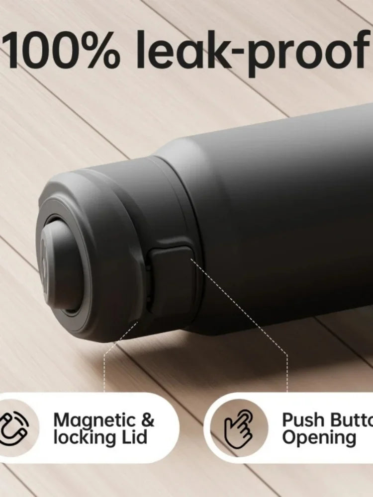 A close-up view of a black insulated sports water bottle with a magnetic and locking lid on a wooden surface.