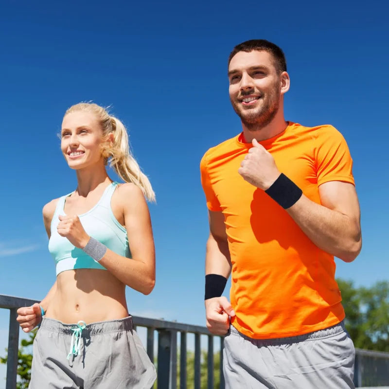 A woman and a man jogging outdoors wearing multi-sport breathable wristbands.