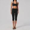 A woman models a black two-piece yoga and sports tracksuit set consisting of a cropped top and full-length leggings.