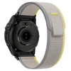 A black Garmin sports watch with a light gray nylon strap and a yellow accent.