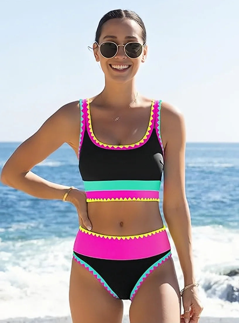 A woman models a color-block zigzag three-piece swimsuit set in black and neon pink on a sunny beach.