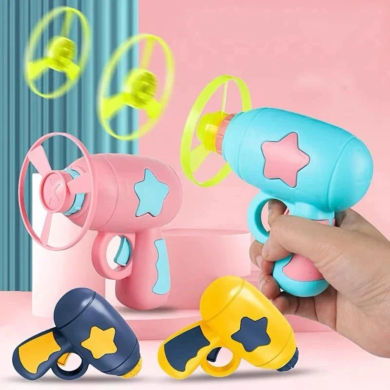 Une main tient un jouet à lancer interactif rose et bleu pour chats avec plusieurs disques jaunes visibles.