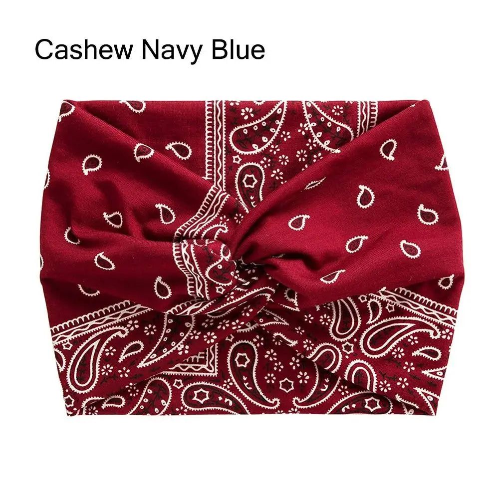A deep maroon fabric headband featuring white paisley and geometric patterns, tied in a cross knot.