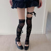Person in sheer black tie-up thigh-high leg warmers and a black ruffled skirt