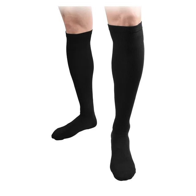 A pair of black compression socks being worn on a person's lower leg.