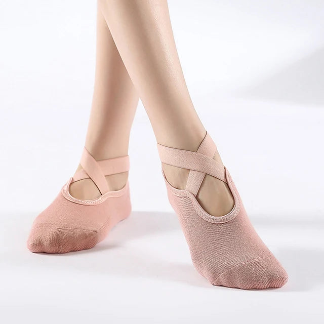 Pair of nude pink breathable silicone yoga and pilates socks worn on a person's feet.