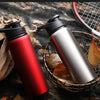 A red and silver leakproof portable aluminum water bottle is shown resting on a woven basket with autumn leaves.