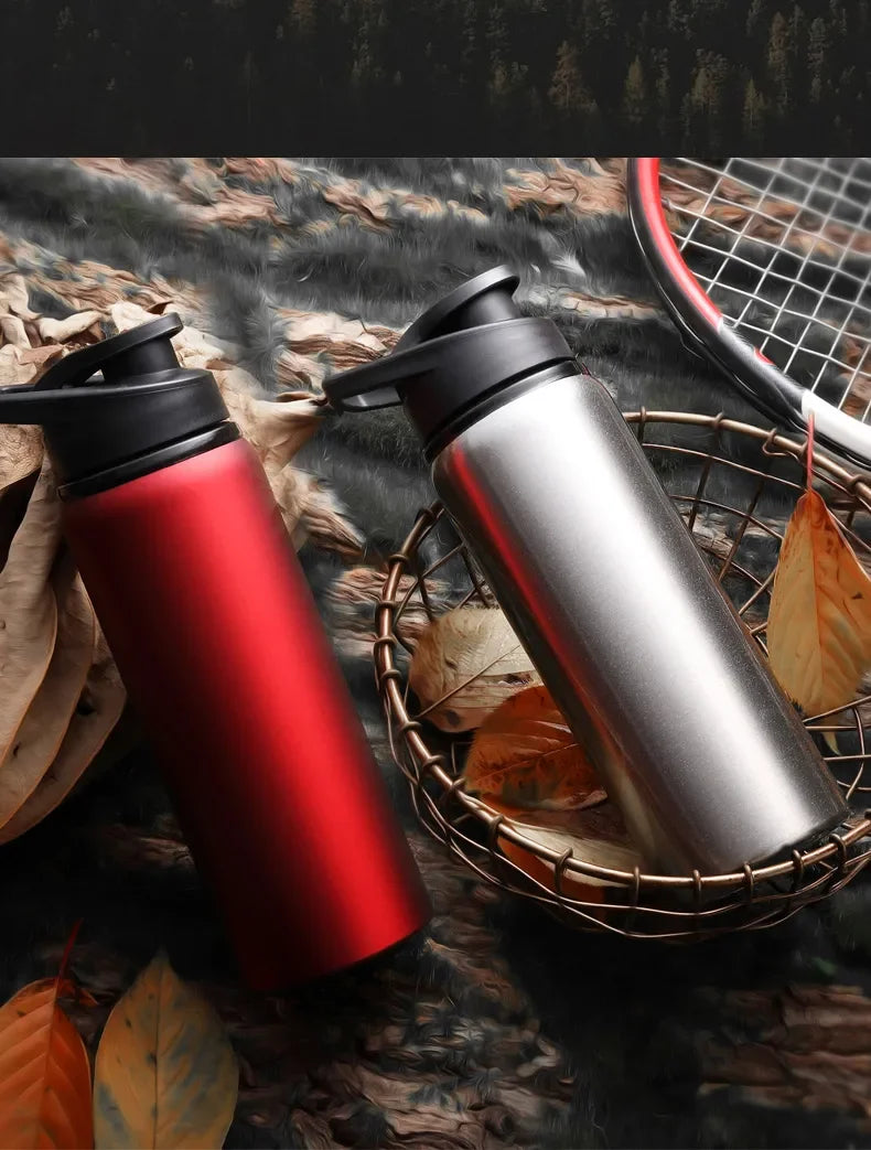 A red and silver leakproof portable aluminum water bottle is shown resting on a woven basket with autumn leaves.