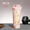 A pink portable electric shaker bottle filled with a yellowish liquid, shown next to a black shaker attachment.