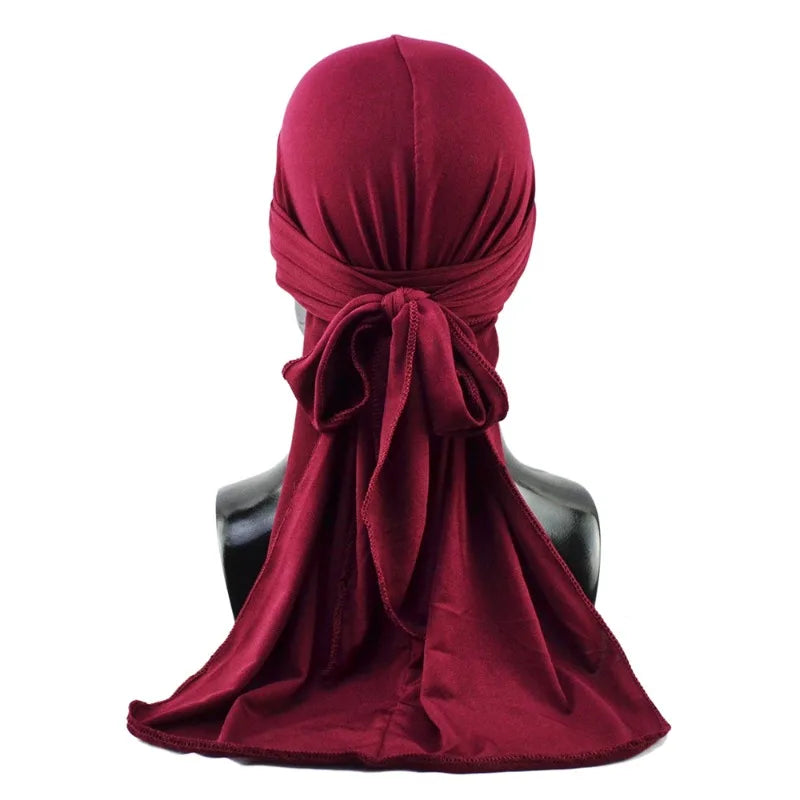 A deep maroon men's distressed pirate style durag head wrap tied around a mannequin neck.