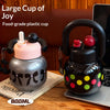 Una taza de plástico oscura diseñada para la alegría junto a una botella aislada negra con tapa roja y lunares amarillos