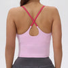 Back view of a women's pink athletic crisscross tank top and gray skirt.