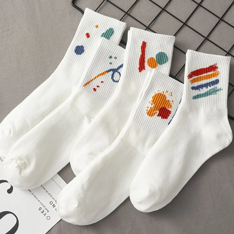 A stack of five white breathable cotton socks featuring colorful abstract designs on the toes.