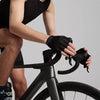 A person wearing black cycling gloves is gripping the handlebars of a bicycle.
