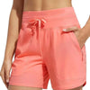 A close-up of a woman wearing coral pink high-waisted quick-dry athletic shorts.