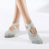 Gray breathable silicone yoga and pilates socks worn on a person's feet.