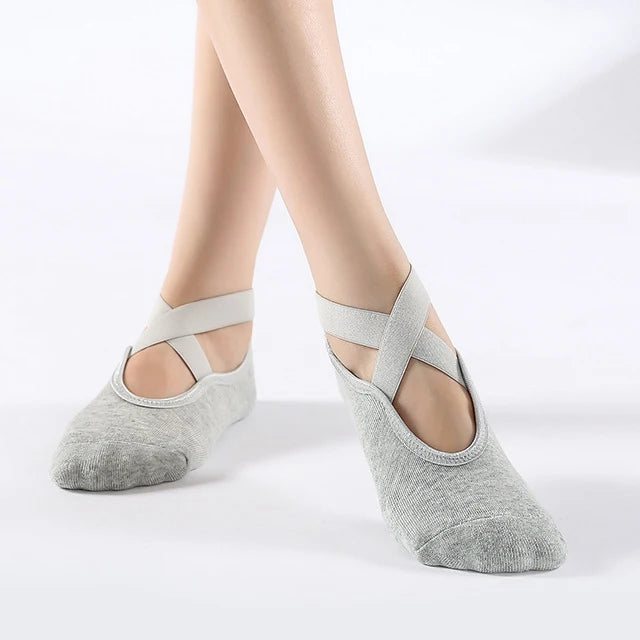 Gray breathable silicone yoga and pilates socks worn on a person's feet.