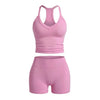 A pink two-piece women's yoga set featuring a racerback tank top and matching shorts.