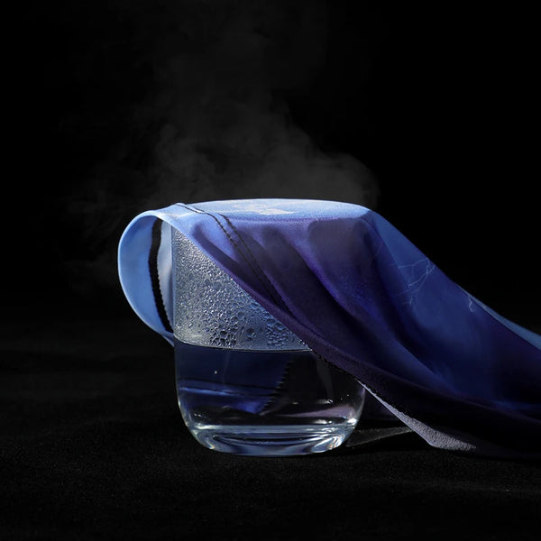 A purple UV protection cooling arm sleeve is shown draped over a glass, with smoke rising in the dark.