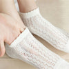 White breathable mesh lace tube socks being worn on a foot and hand.