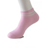 Pink non-slip grip socks with light green stripes worn on a white model's foot.