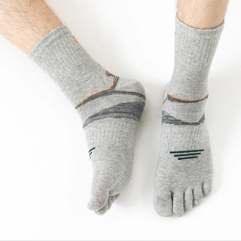 A pair of gray men's sport compression socks with orange accents shown on a foot.