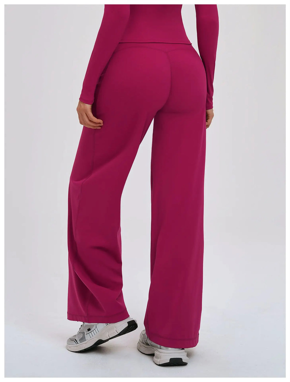 A model wearing magenta high-waist wide-leg yoga leggings and gray sneakers.