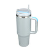 Tasse isotherme en acier inoxydable argenté avec couvercle et paille bleu clair, vue de côté.