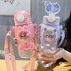 A hand holds a pink and purple leak-proof water bottle shaped like a cartoon animal.