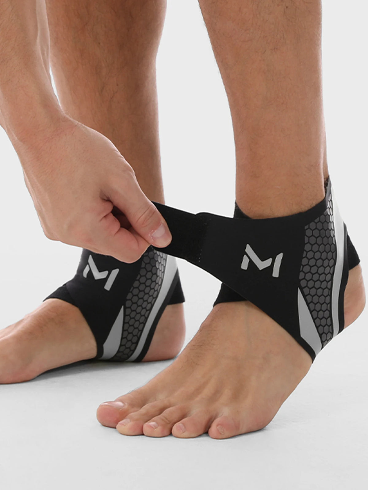 A person's foot is shown wearing black and gray compression ankle support foot sleeves.