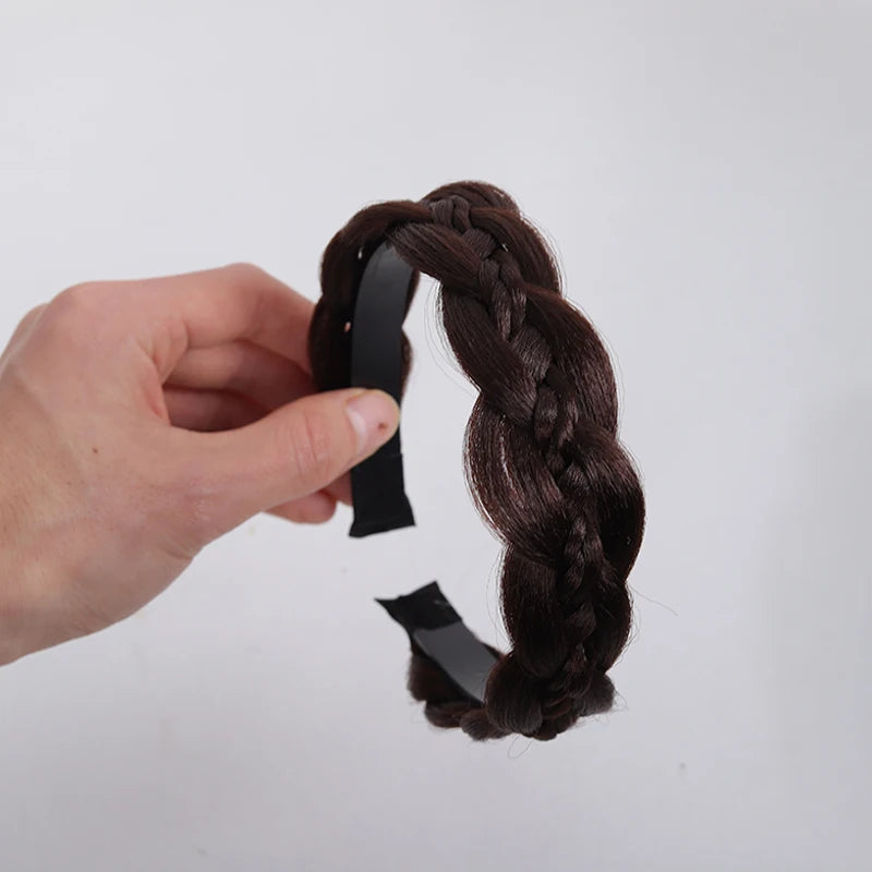 A hand is holding a dark brown twisted braided wig headband.