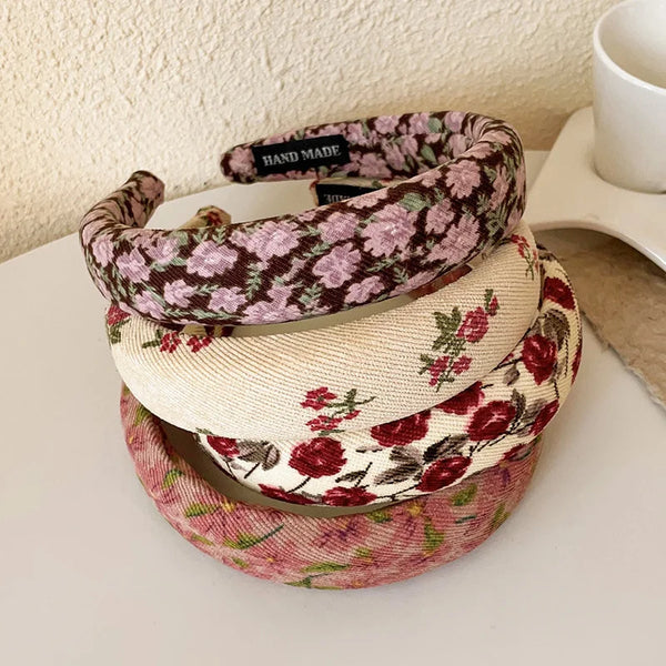 Three floral print hair headbands stacked on a white surface.