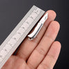 Un mini cuchillo llavero plegable de latón se muestra apoyado en una mano junto a una regla para escala.