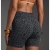 Une femme portant des shorts de yoga taille haute à imprimé léopard et un haut orange, vue de dos.