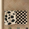 A pair of black and white patterned soft coral fleece face towels hanging on a tiled wall.