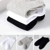 Una pila de calcetines de algodón unisex transpirables, en varios tonos como gris, blanco y negro.