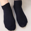 A pair of black bamboo fibre anti-odor socks shown on a hand.