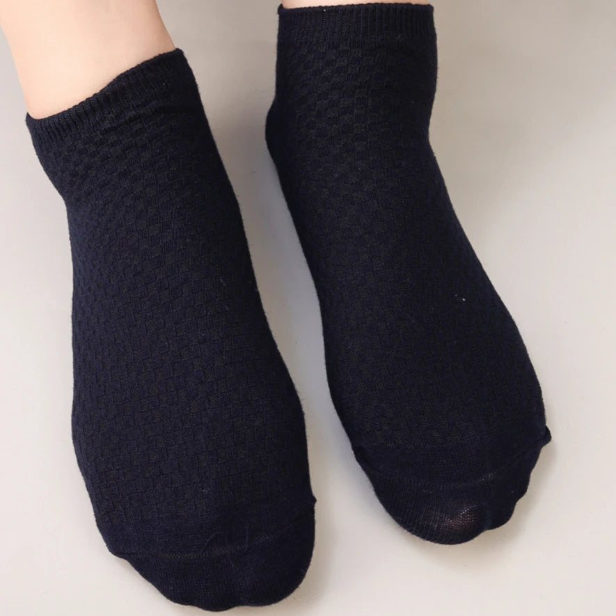 A pair of black bamboo fibre anti-odor socks shown on a hand.