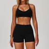 A woman wearing a black 3-piece yoga sports set consisting of a crop top and shorts.