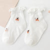 A pair of white baby socks with ruffled cuffs and small orange-colored embroidery on the toes.