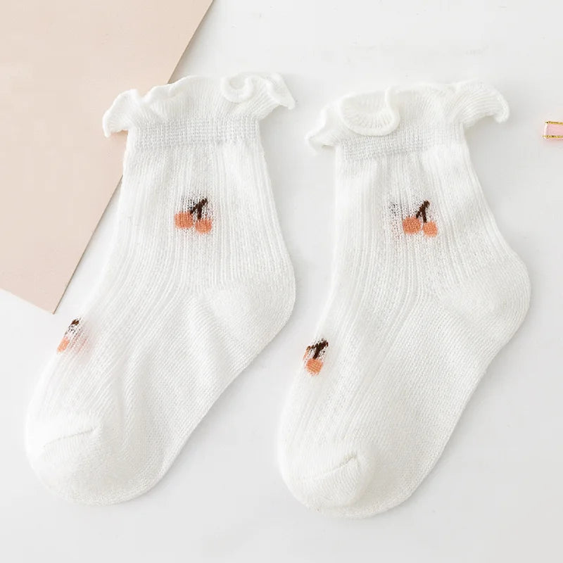 A pair of white baby socks with ruffled cuffs and small orange-colored embroidery on the toes.
