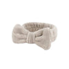 A beige microfiber spa headband and wristband set folded into a bow shape.