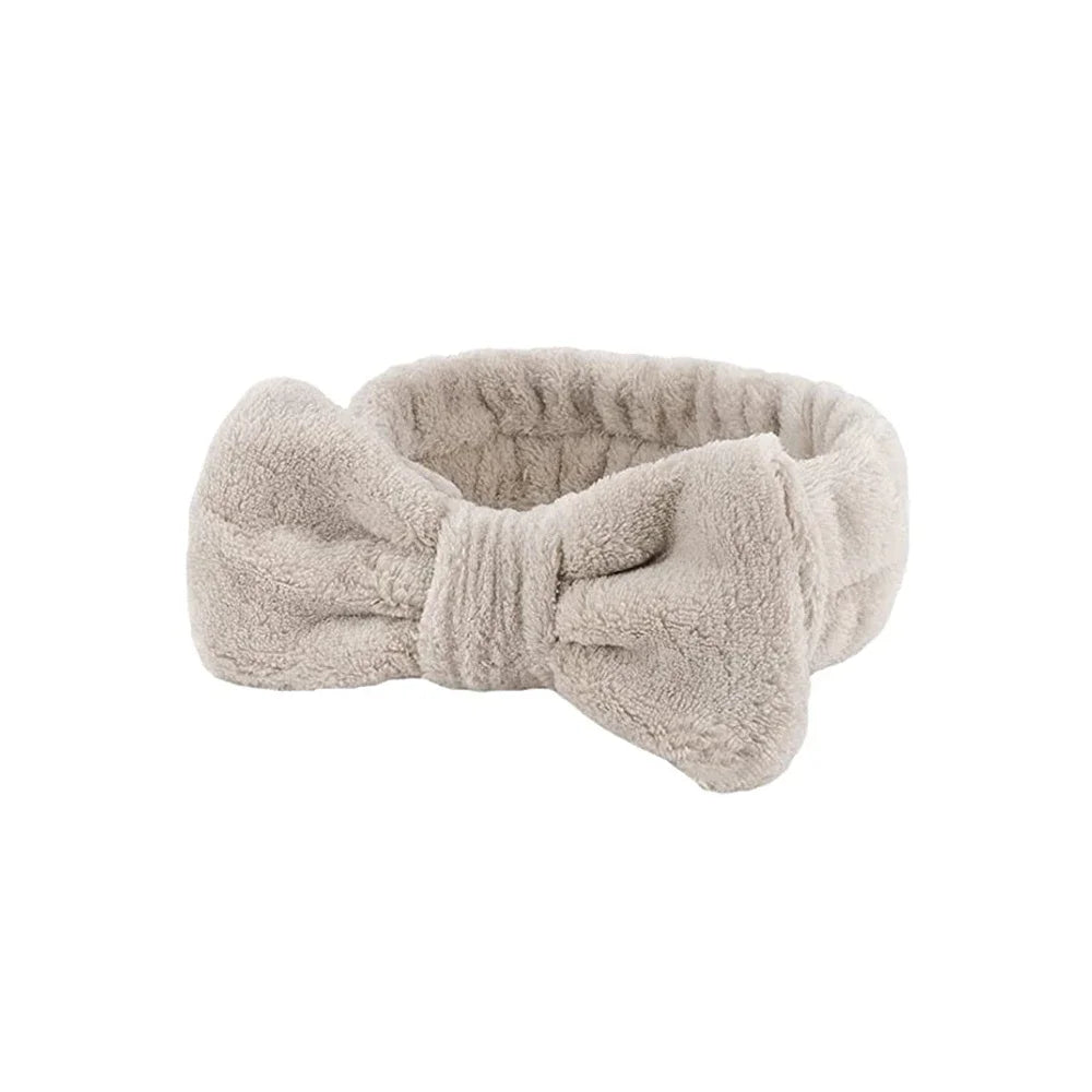 A beige microfiber spa headband and wristband set folded into a bow shape.